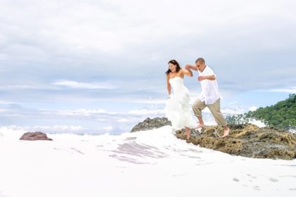Bride and groom jumping from rock.
