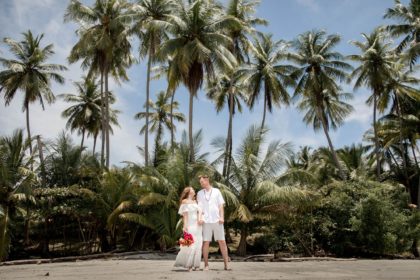 Bride and groom on the beach with lovely palm tree background.