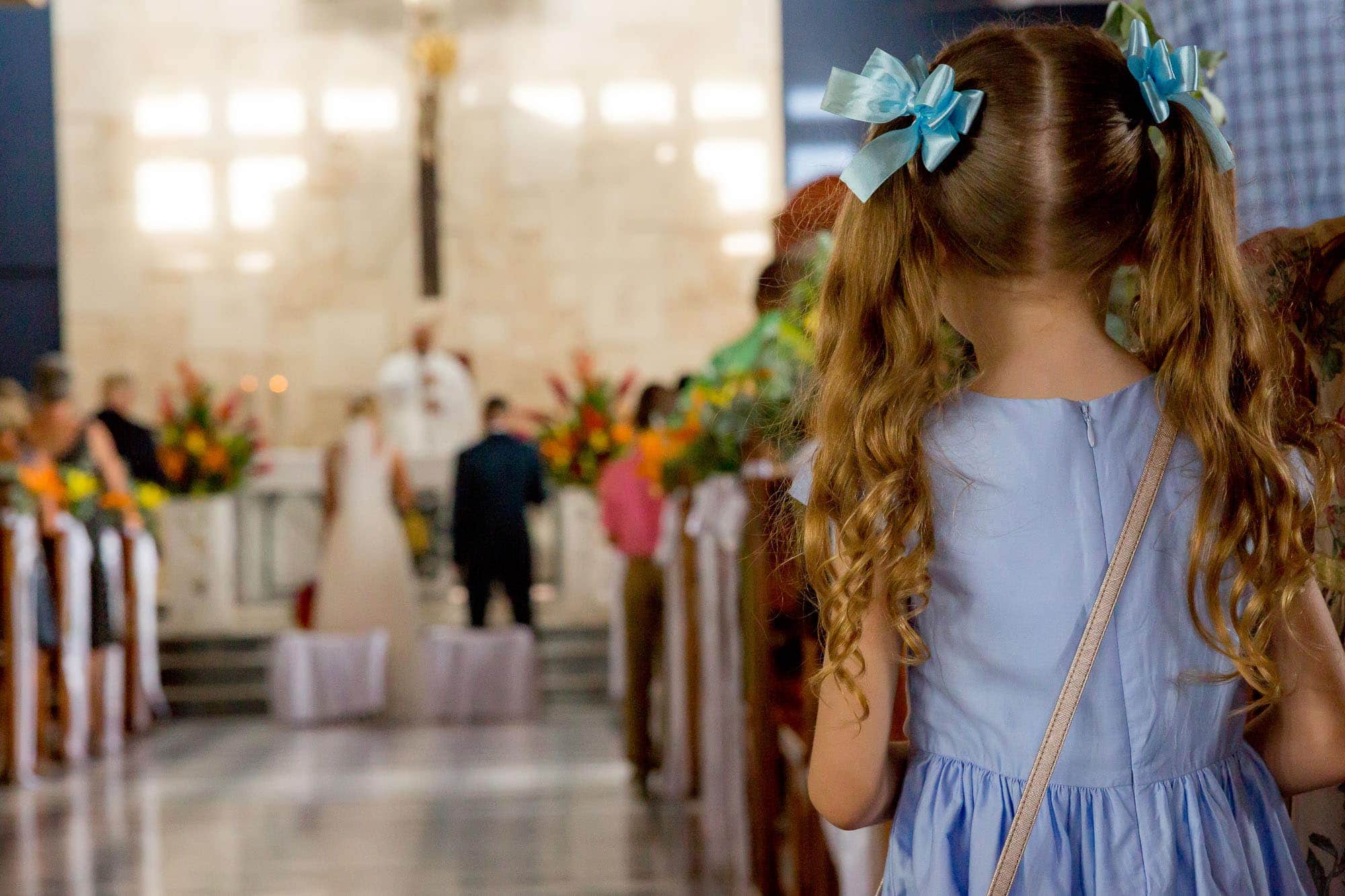 Little girl stands attentively watching the church wedding ceremony