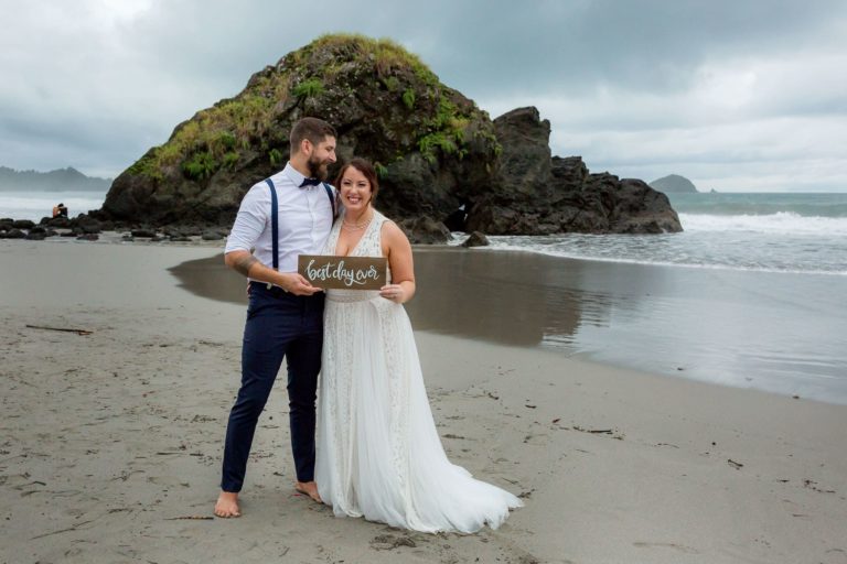 Bride and groom on the beach with sign "best day ever"