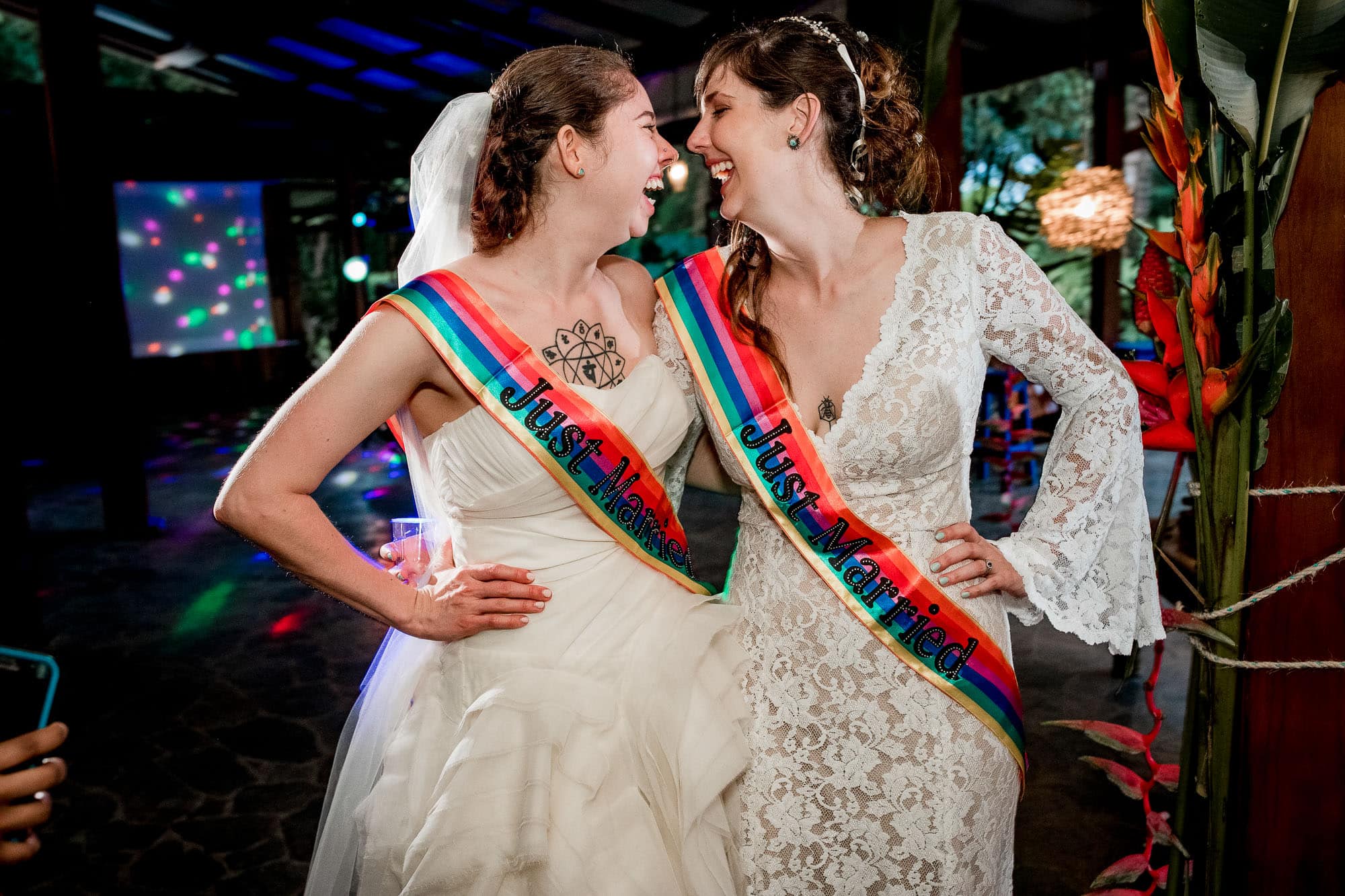 two brides with rainbow sashes