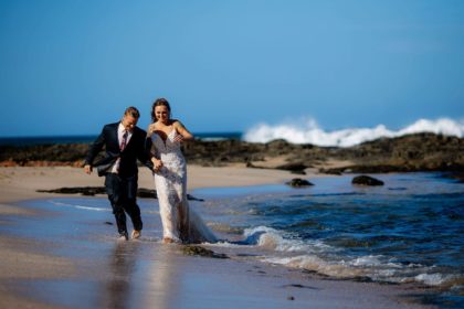 The tattooed bride and groom walking along Langosta Beach