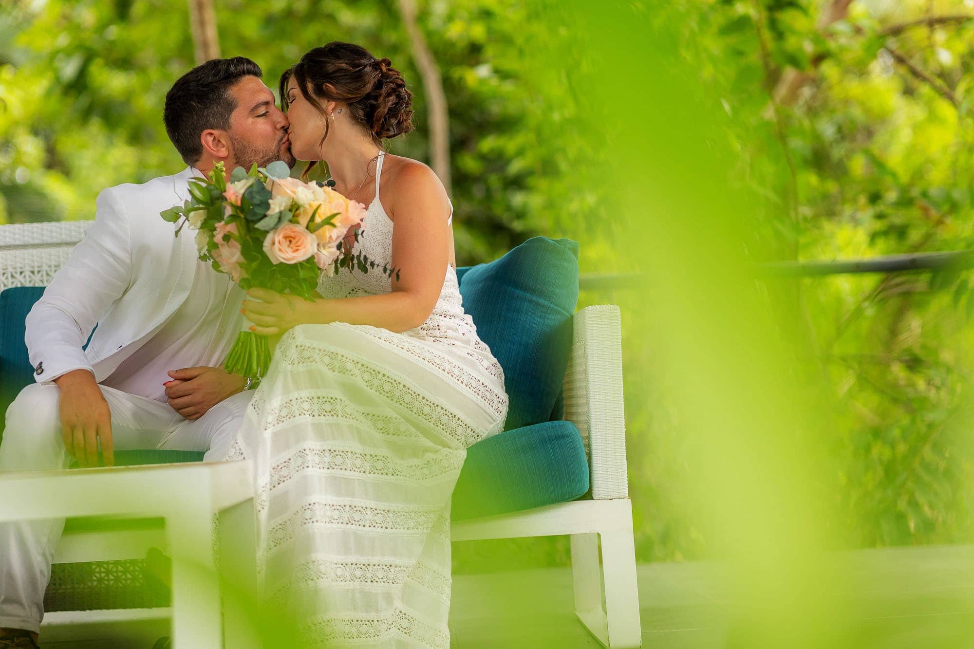 The bride and groom sneak a kiss on a bench