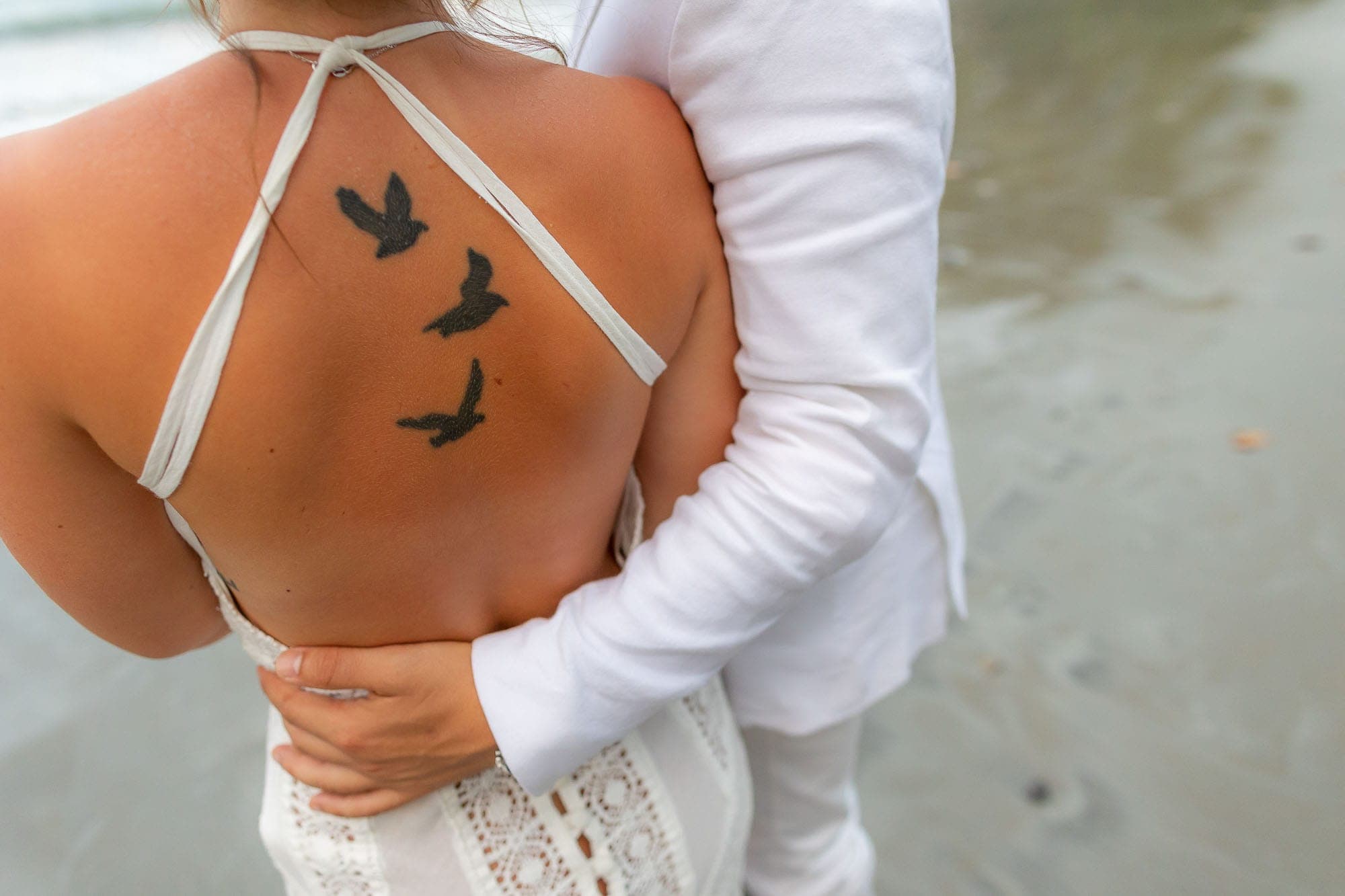 Closeup of the three birds tattoo on the bride's back