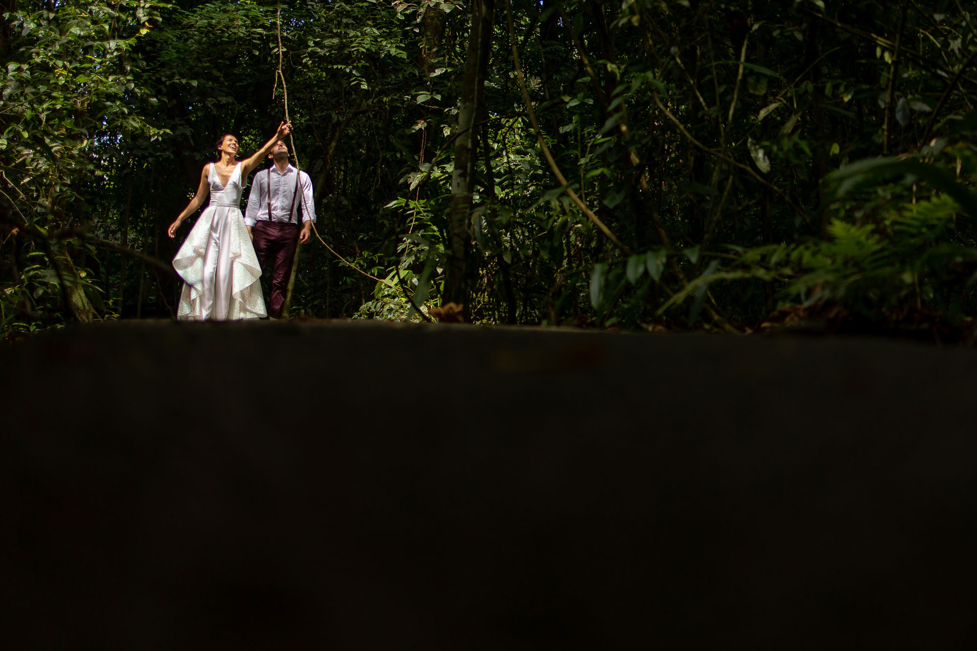 the bride and groom having fun as they walk through manuel antonio national park