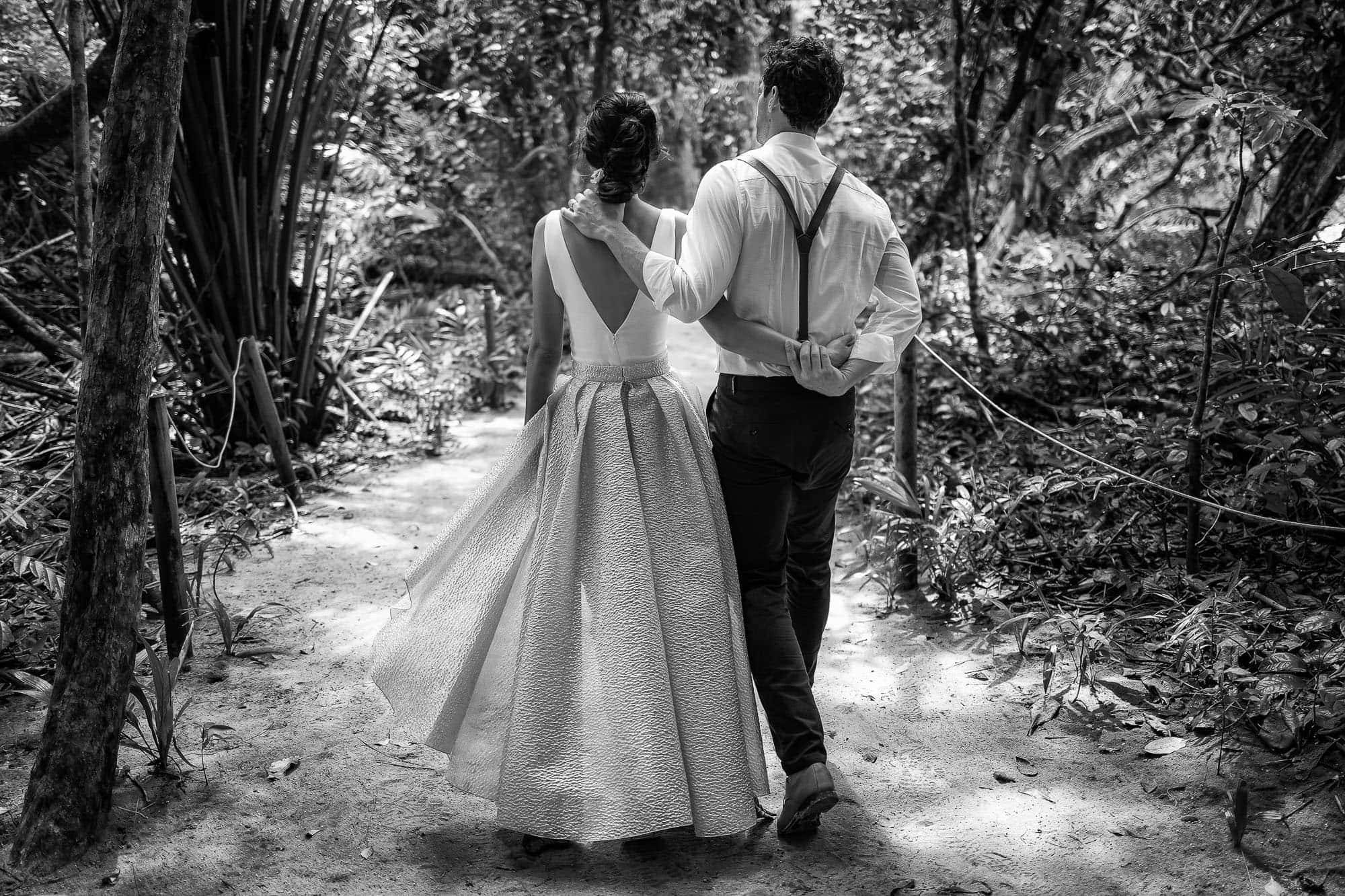 the bride and groom having fun as they walk through manuel antonio national park