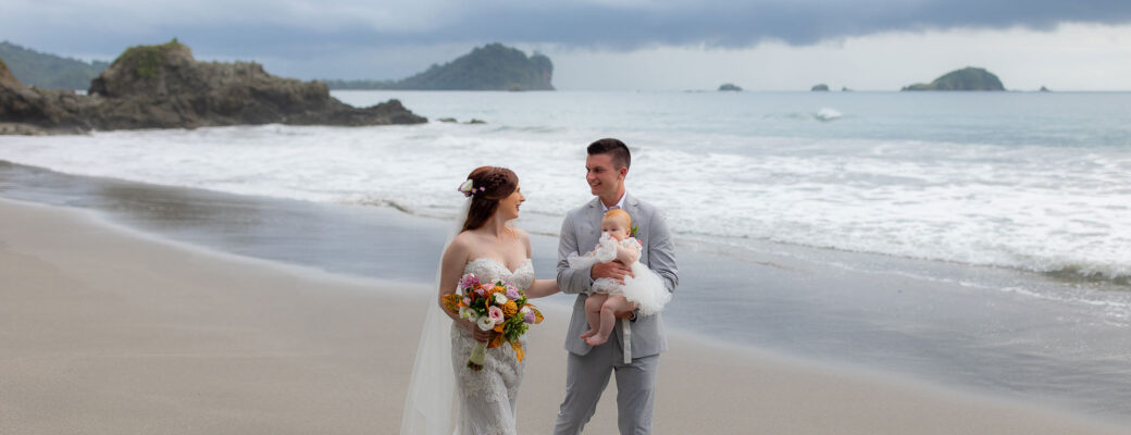 Groom, bride, and baby stroll along the beach at a costa rica wedding