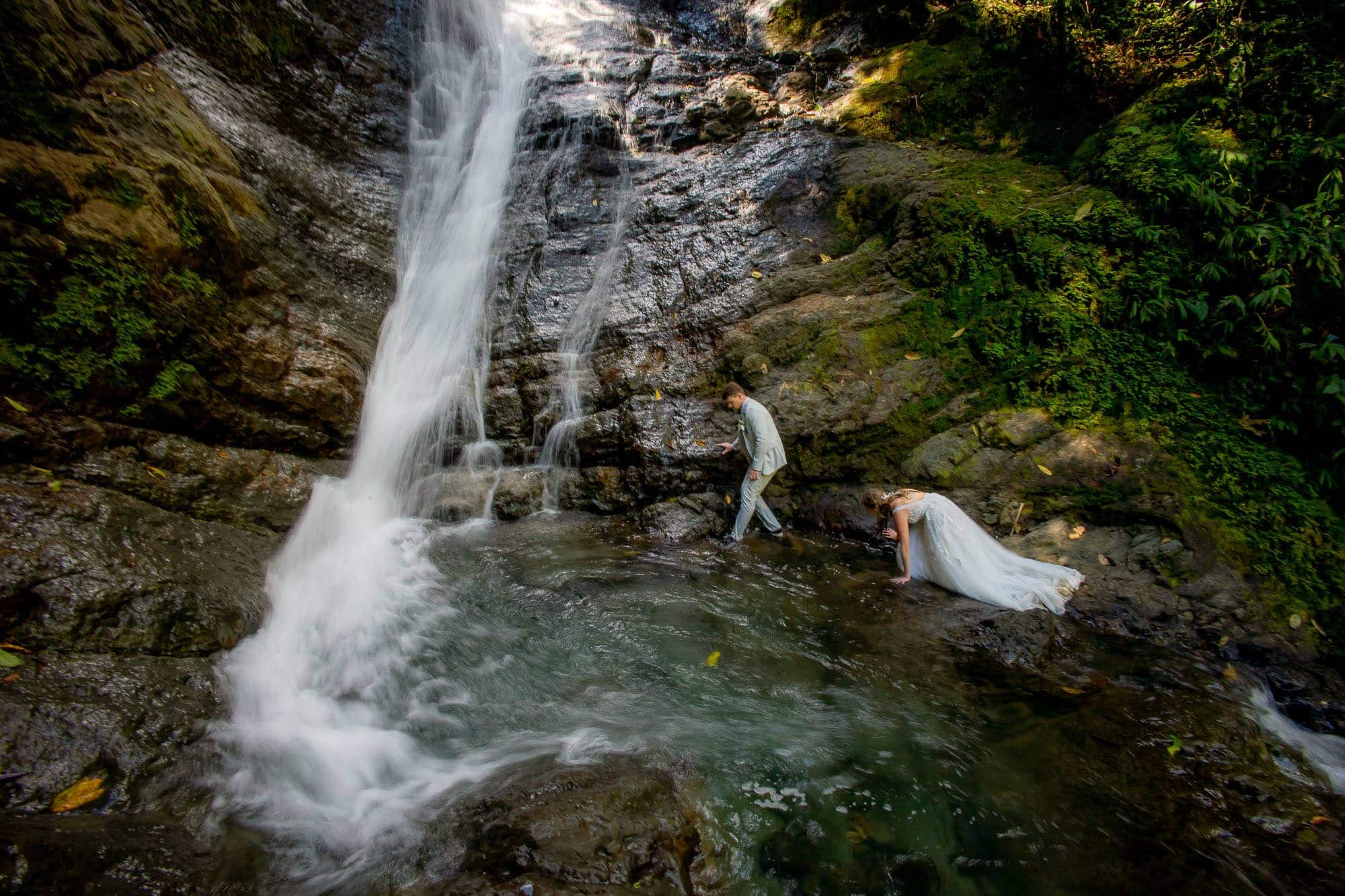 Bride and groom walking in the waterfall at their waterfall wedding