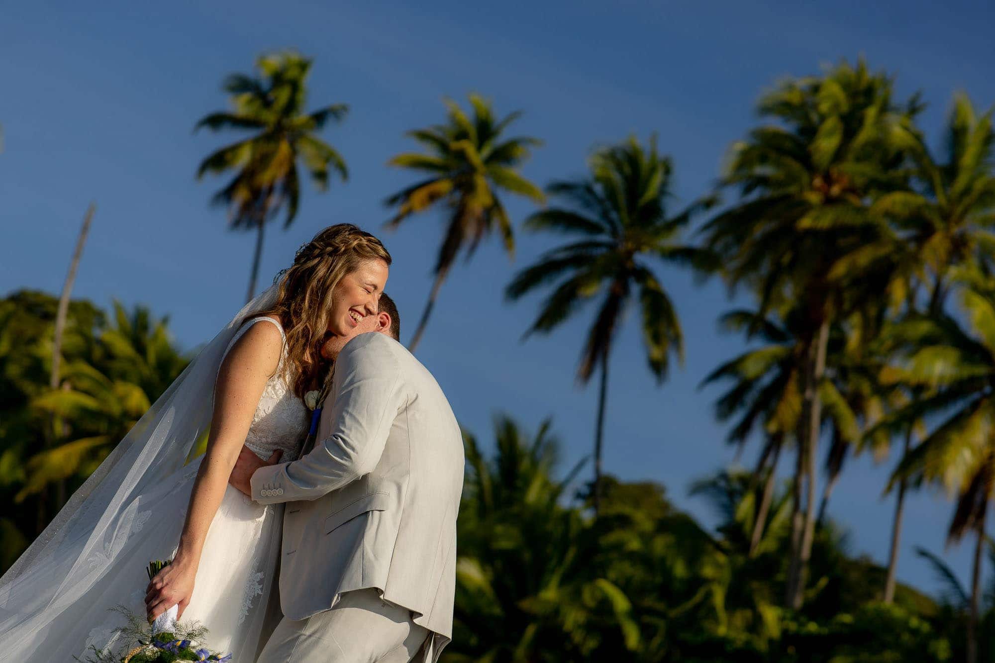 Bride and groom snuggling on the beach