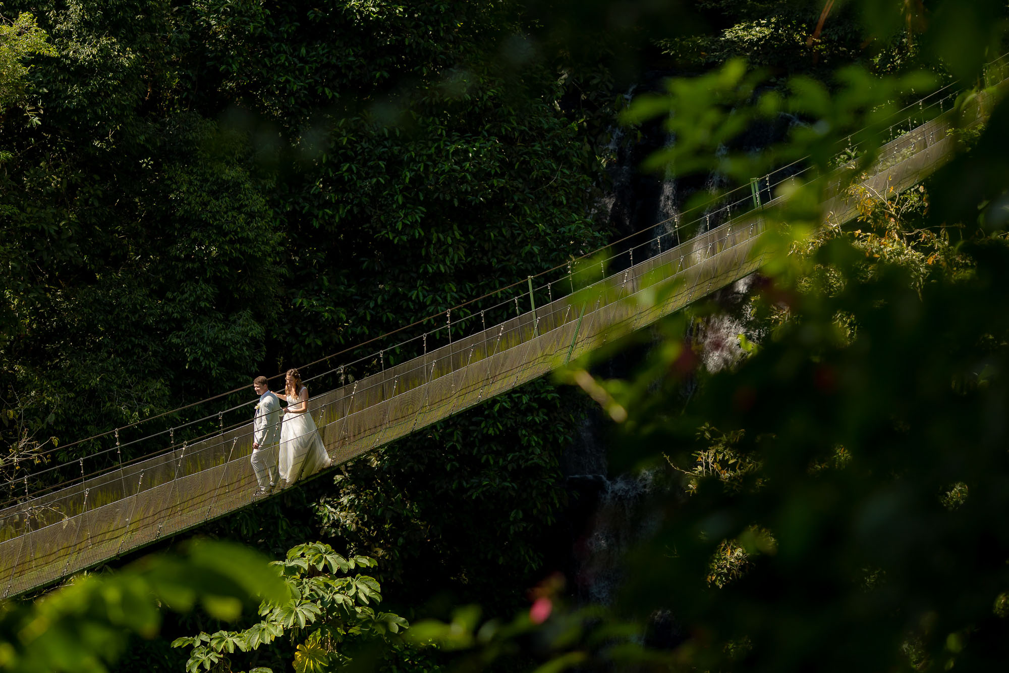 Bride and groom on a hanging bridge at a waterfall wedding