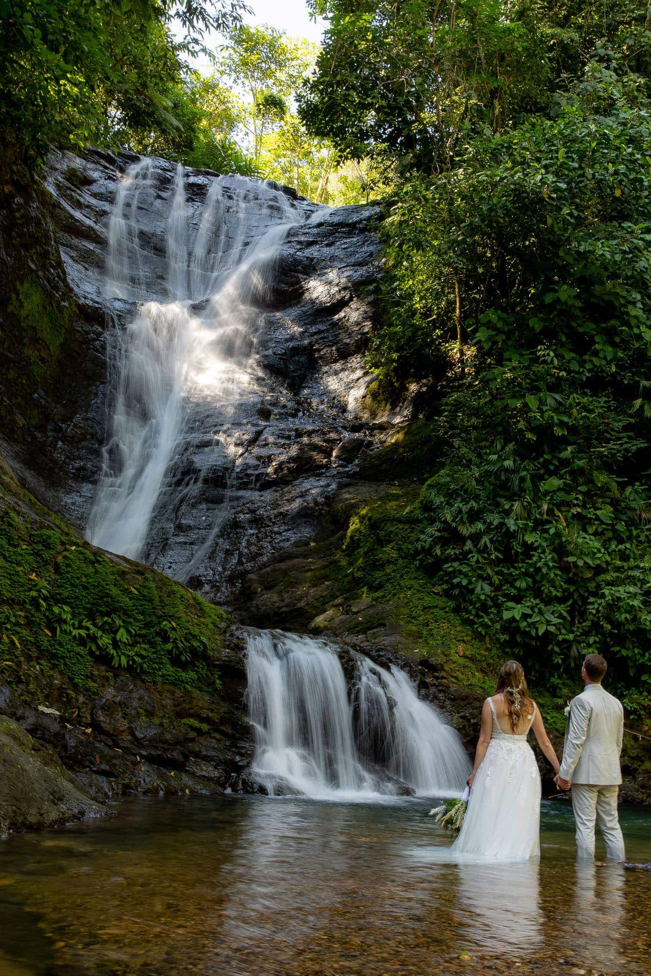 bride and groom at the base of the waterfall