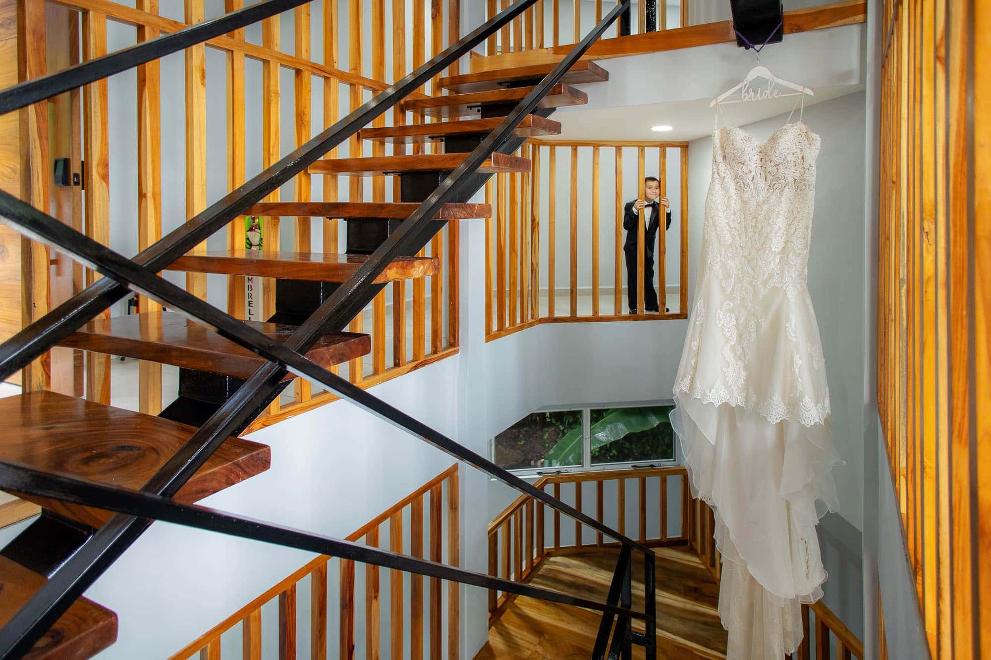 Kid peeks at the wedding dress hanging in an unusual stairwell