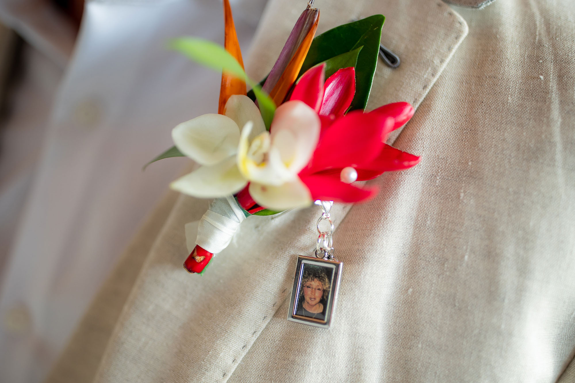 closeup of the groom's boutonniere, complete with keychain photo of his mom