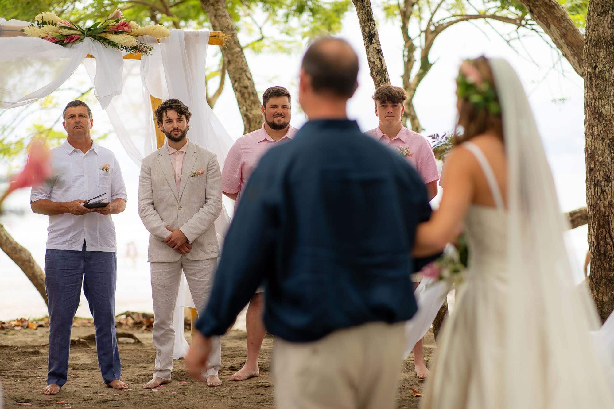 second photographer angle of groom seeing bride walk down aisle