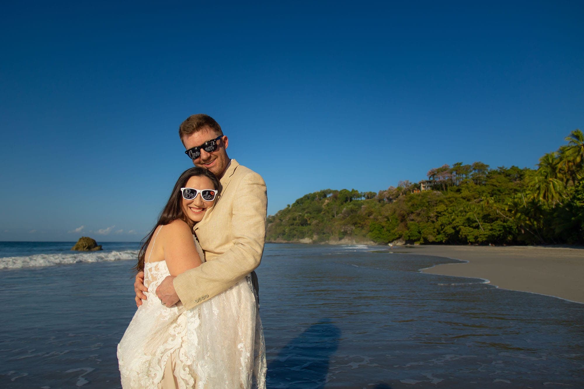 bride and groom on the beach with bride and groom sunglasses