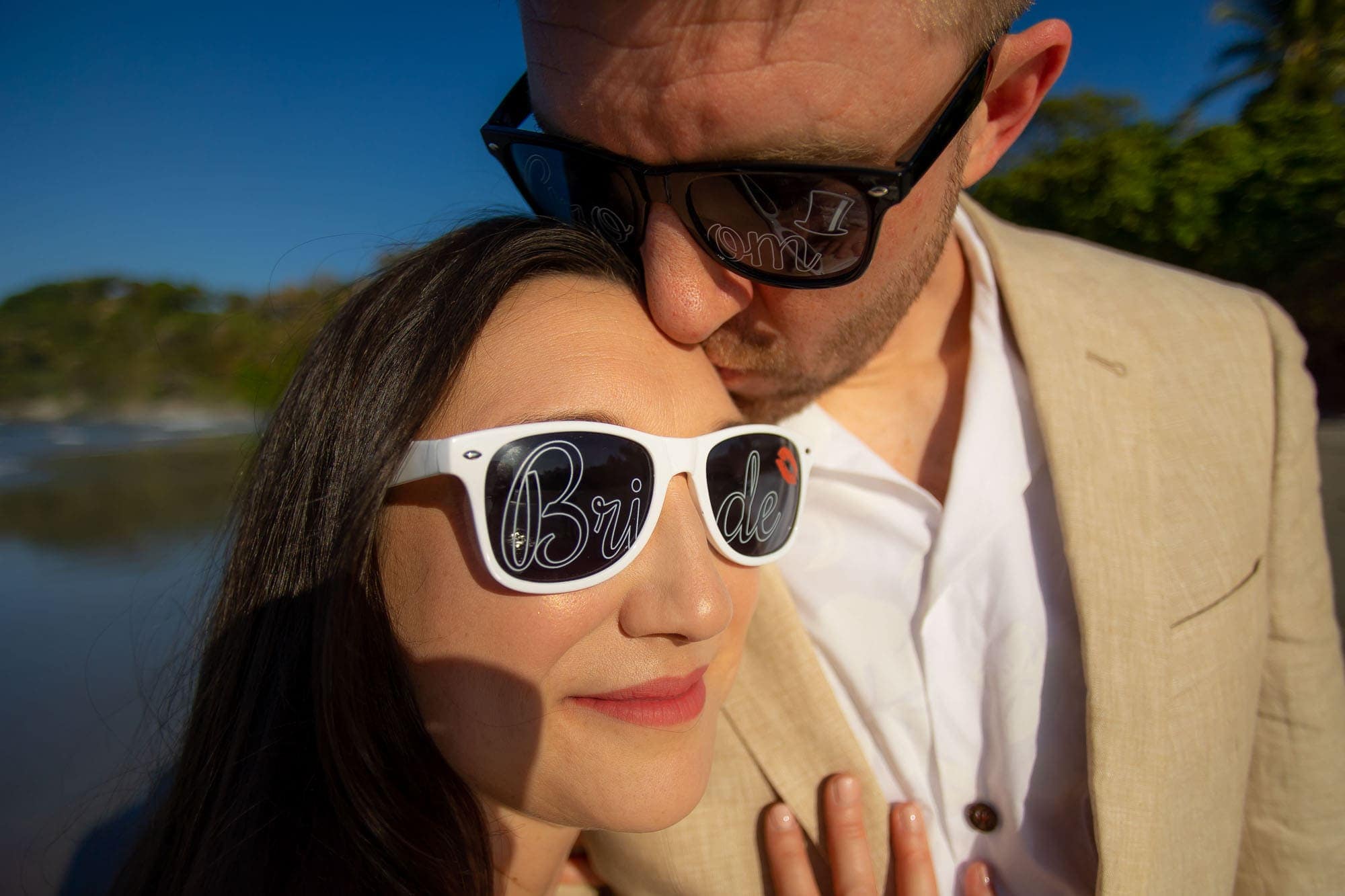 bride and groom on the beach with bride and groom sunglasses