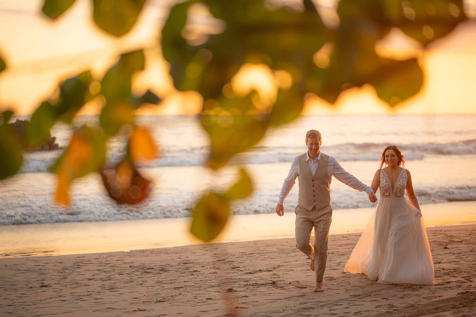 wedding couple strolling along the beach at sunset