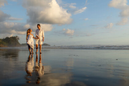 The happy couple walks along Roca Verde Beach in Dominical