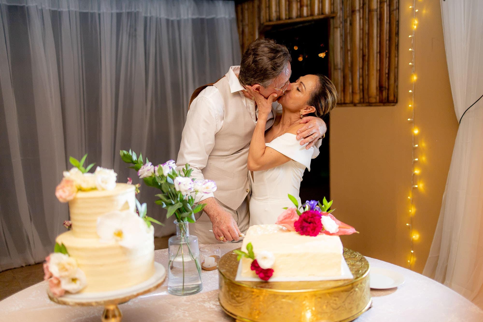 The bride and groom share a kiss with the cake