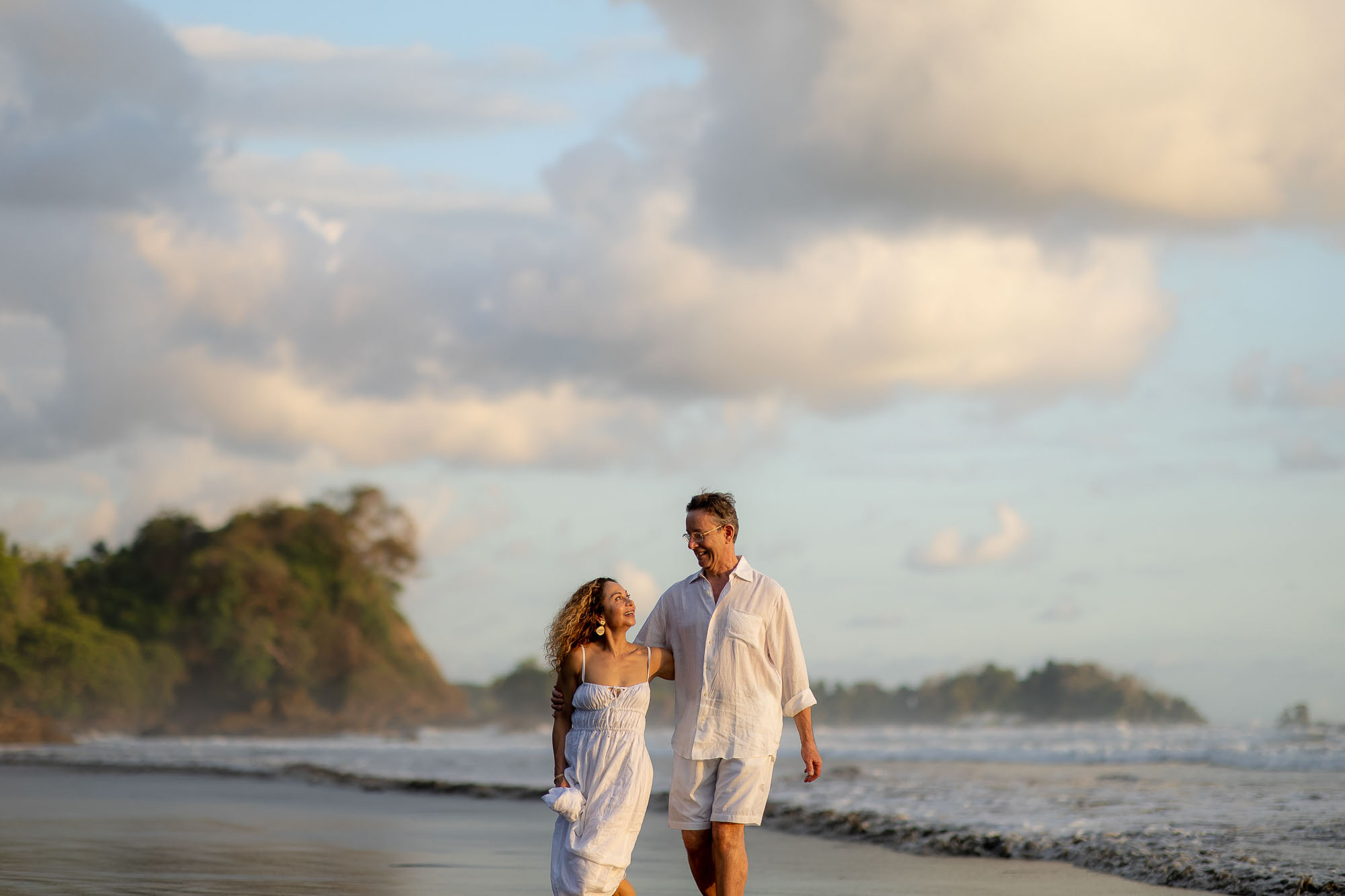 The happy couple walks along Roca Verde Beach in Dominical