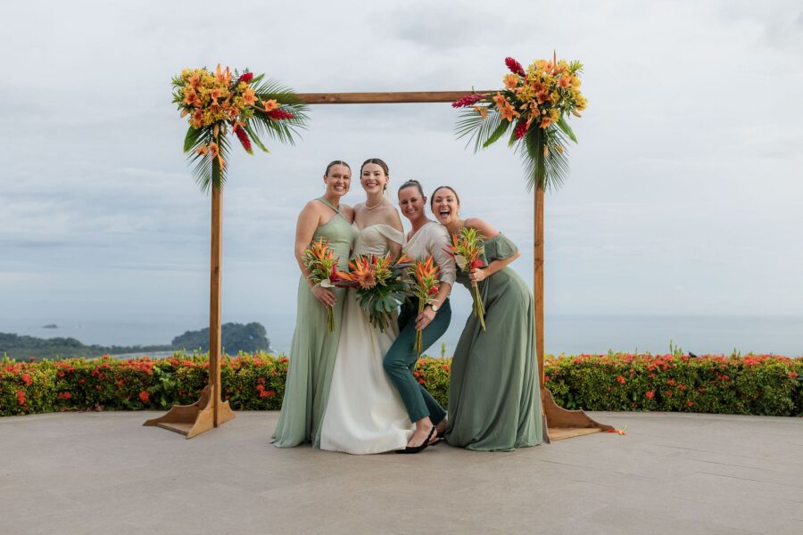 bride and bridesmaids pose with arbor and spectacular view