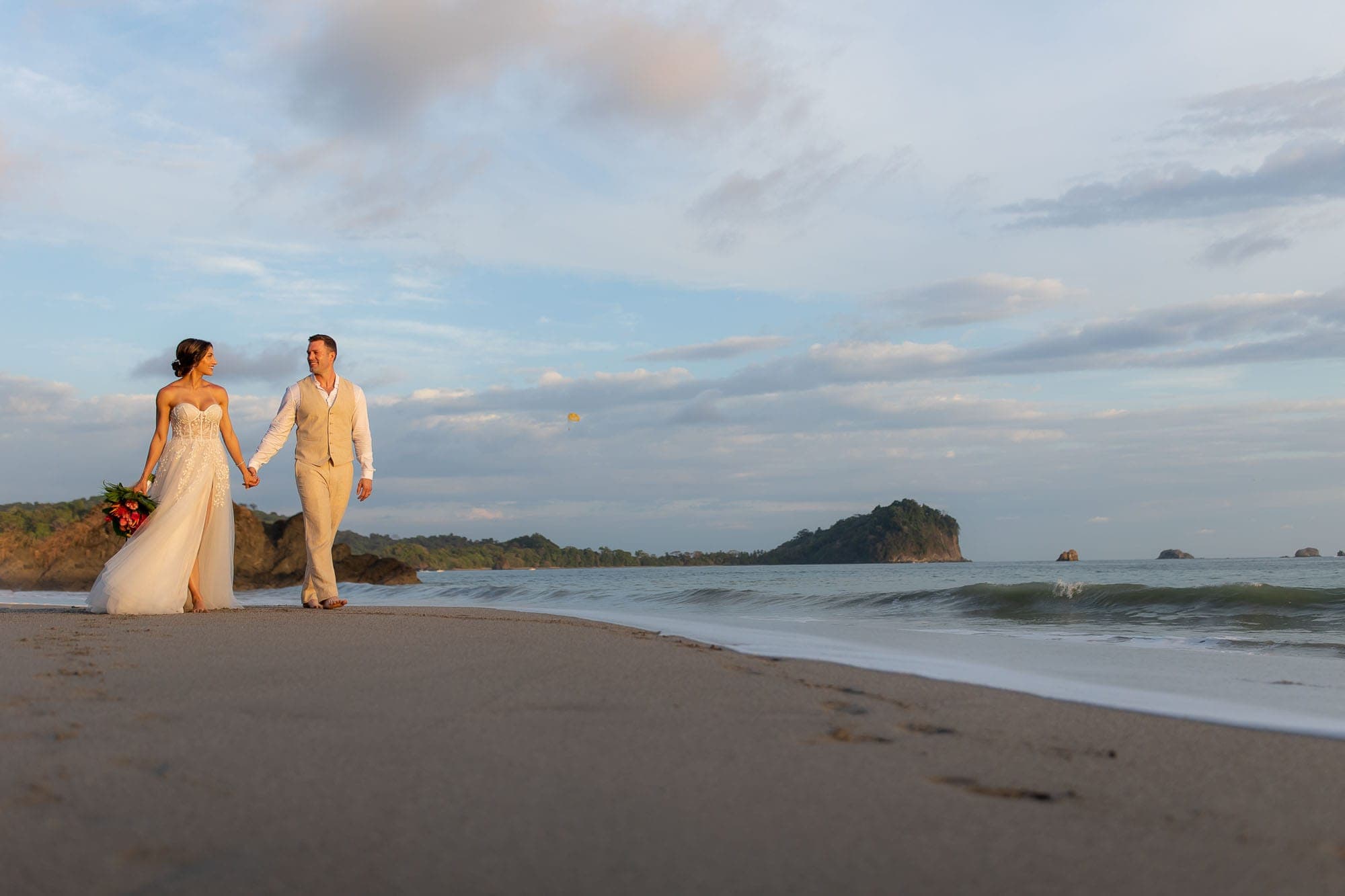 bride and groom walk along the beach
